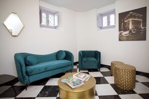 Ein Zimmer mit taubenfarbenen Sofas, einem goldfarbenen Couchtisch und einem Schachbrettmuster-Boden.