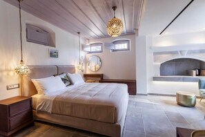 Ein Schlafzimmer mit Bett, Nachttischen, Kommode, Spiegel, Kamin und Pendelleuchten.