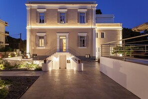 A two-story building with a central entrance, a staircase leading to the upper floor, and a balcony on the right side. - Aylin Executive Suites - Saray Suite (Rhodes)