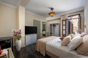 Ein Hotelzimmer mit Bett, Fernseher, Kleiderschrank und einem kleinen Tisch mit einer Vase.