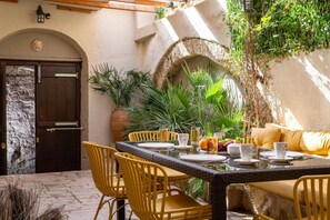 Comedor con pared de piedra, puerta de madera y sillas amarillas.
