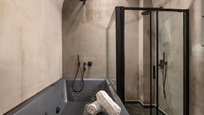 Et moderne badeværelse med badekar, bruser og brusekabine med glasvægge.