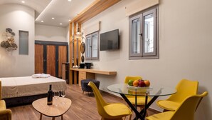 Ett modernt hotellrum med en säng, ett glasbord, gula stolar, en tv och ett träpanelat tak.