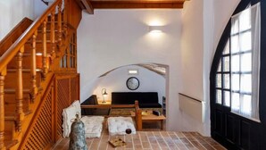 A room with a wooden staircase, a clock on the wall, a fireplace, and a large window. - Belvedere Medieval Villa in Old Town (Old Town Rhodes)