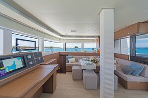 A modern interior with a control panel, seating area, and large windows offering ocean views. - Sun-Kissed Sailing Adventure in Islas Sarónicas (Alimos)