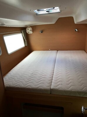 A compact RV interior with a single bed, a small window, and a ceiling-mounted light fixture. - Sun-Kissed Sailing Adventure in Isla de Mahe, Seychelles (Providence)