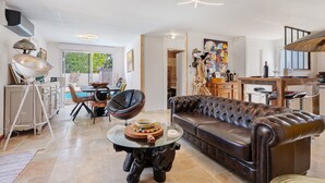 A spacious living room with a leather sofa, a glass coffee table, and a dining area with a modern chair and table.