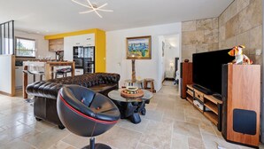 A modern living room with a leather sofa, a round coffee table, a flat-screen TV, and a wooden entertainment unit.