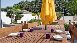 A wooden deck with outdoor dining setup, including tables, chairs, and umbrellas.