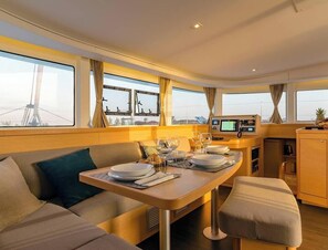 A dining area with a table set for two, a sofa, and a small kitchenette. - Sun-Kissed Sailing Adventure in Isla de Mahe, Seychelles (Mahe)