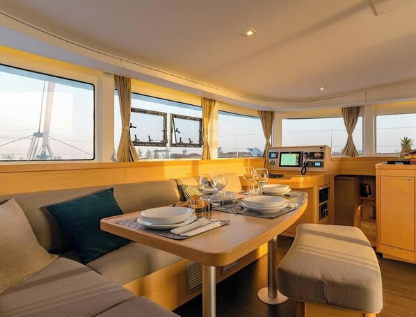 Een eethoek met een tafel gedekt voor twee personen, een bank en een kleine kitchenette.