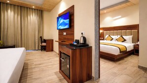 Hotellihuone, jossa on sänky, työpöytä, televisio, kahvinkeitin ja minibaari.