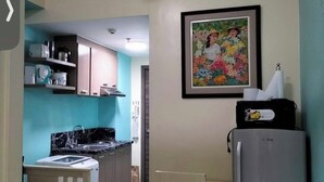 Une cuisine compacte comprenant un coin repas, un réfrigérateur et un tableau accroché au mur.
