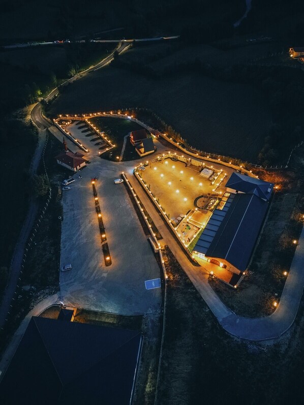 An aerial view of a large, well-lit parking area with multiple buildings, including a prominent red-roofed structure and a large blue building.