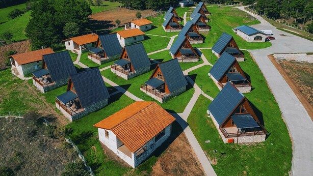 A cluster of A-frame cabins with sloped roofs, arranged in a semi-circular pattern around a central paved area. - KASTİLYA KIRSAL TURİZİM  TESİSİ (Kastamonu)