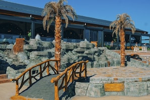 A stone bridge, palm trees, and a building with large windows.
