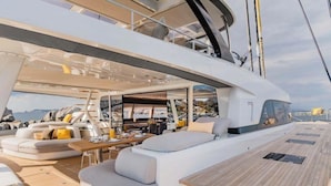 Interior de un yate con comedor, asientos y vista al mar.