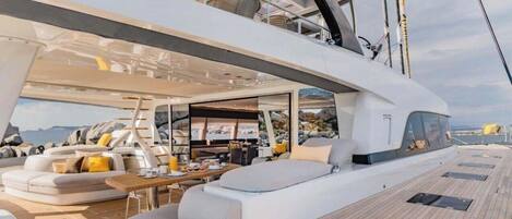 A yacht interior with a dining area, seating, and a view of the sea.
