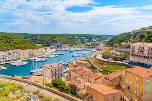 A coastal town with a marina, terraced buildings, and a road leading to the harbor.