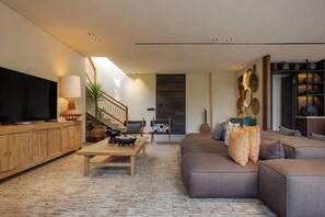 Ein modernes Wohnzimmer mit Sofa, Fernseher, Holzschrank und Treppe.