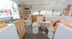 A compact interior with a kitchenette, a dining area, and a seating space. - Sun-Kissed Sailing Adventure in Islas Sarónicas (Alimos)