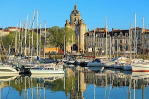 Ein Yachthafen mit mehreren angestuften Booten, im Hintergrund ein markantes historisches Gebäude und ein klarer, blauer Himmel.
