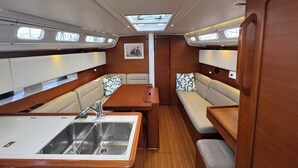 A compact galley with a sink, a small table, and seating with patterned cushions. - Sun-Kissed Sailing Adventure in Antiguo Puerto de La Rochelle (La Rochelle)