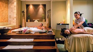Een spa-ruimte met een massagetafel, een persoon die een massage ontvangt, en een ander persoon die ligt te ontspannen.