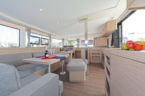 A modern RV interior with a dining area, kitchenette, and seating.