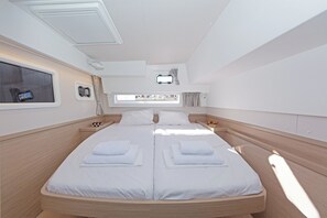 A modern, well-lit bedroom with a large bed, a small window, and a control panel.