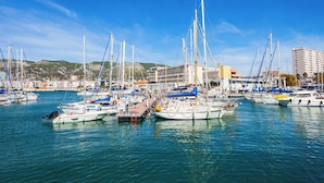 Un port de plaisance où sont amarrés de nombreux bateaux, un bâtiment doté d’un toit plat et, au loin, un paysage vallonné.