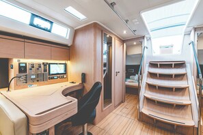 A control panel with multiple screens and a desk, a chair, and a staircase with wooden steps. - Sun-Kissed Sailing Adventure in Islas Sarónicas (Alimos)