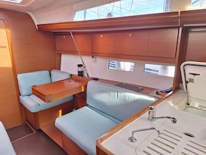 A compact galley with a wooden countertop, two cushioned seating areas, a small sink, and a window above the sink.