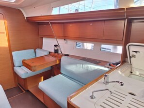 A compact galley with a wooden countertop, two cushioned seating areas, a small sink, and a window above the sink.