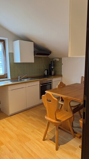 Une cuisine équipée d’un évier, d’une cuisinière et d’une table à manger en bois avec des chaises.