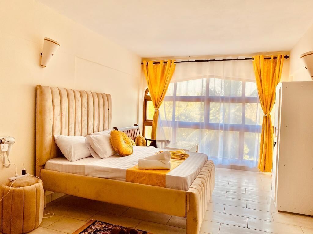 Ein Schlafzimmer mit Bett, Heizkörper, Nachttisch und einem Fenster mit Vorhängen.