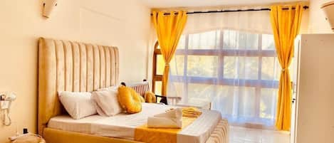 A bedroom with a bed, a radiator, a bedside table, and a window with curtains.