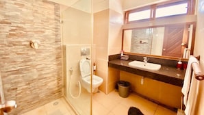 Ein modernes Badezimmer mit Duschkabine aus Glas, Toilette, Waschbecken und einem großen Spiegel.