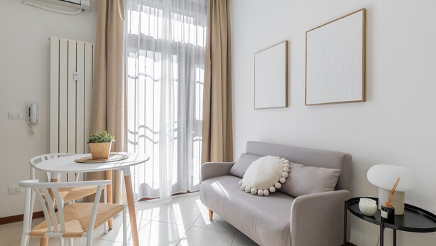A modern living room with a sofa, a small round table, and a chair. - Light-Filled Flat by Wonderful Italy (Bologna)