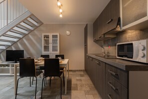 Eine moderne Küche mit Mikrowelle, Schränken und einem Essbereich mit Stühlen und Tisch.