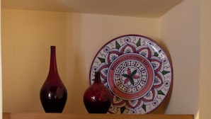 Een plank met decoratieve objecten, waaronder een bord, twee vazen, een lamp en een klein potje.