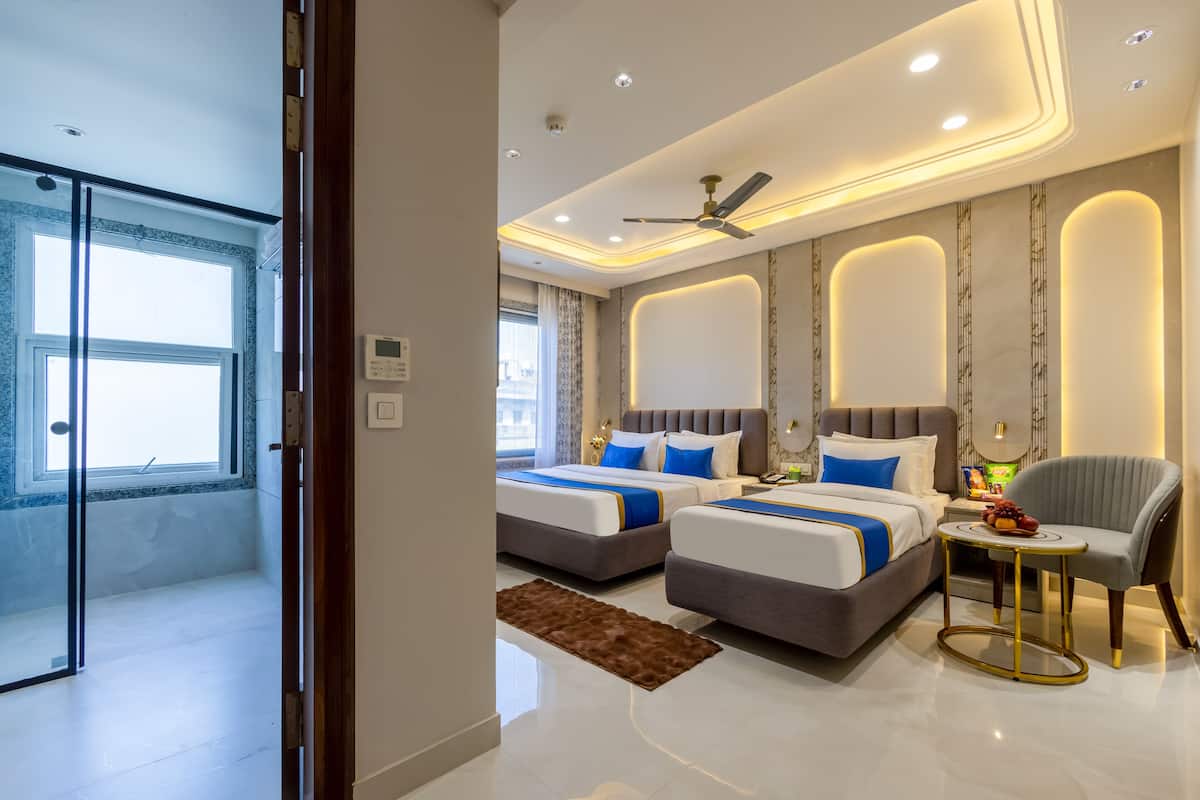 A modern hotel room with two beds, a ceiling fan, and a small table with a chair.