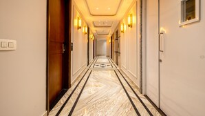 A hotel hallway with a marble floor, wall sconces, and a door at the end. - Anu Plaza-5Mins from Connaught Place (New Delhi)