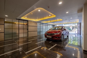 Un interior moderno con un coche rojo, suelos reflectantes e iluminación empotrada.