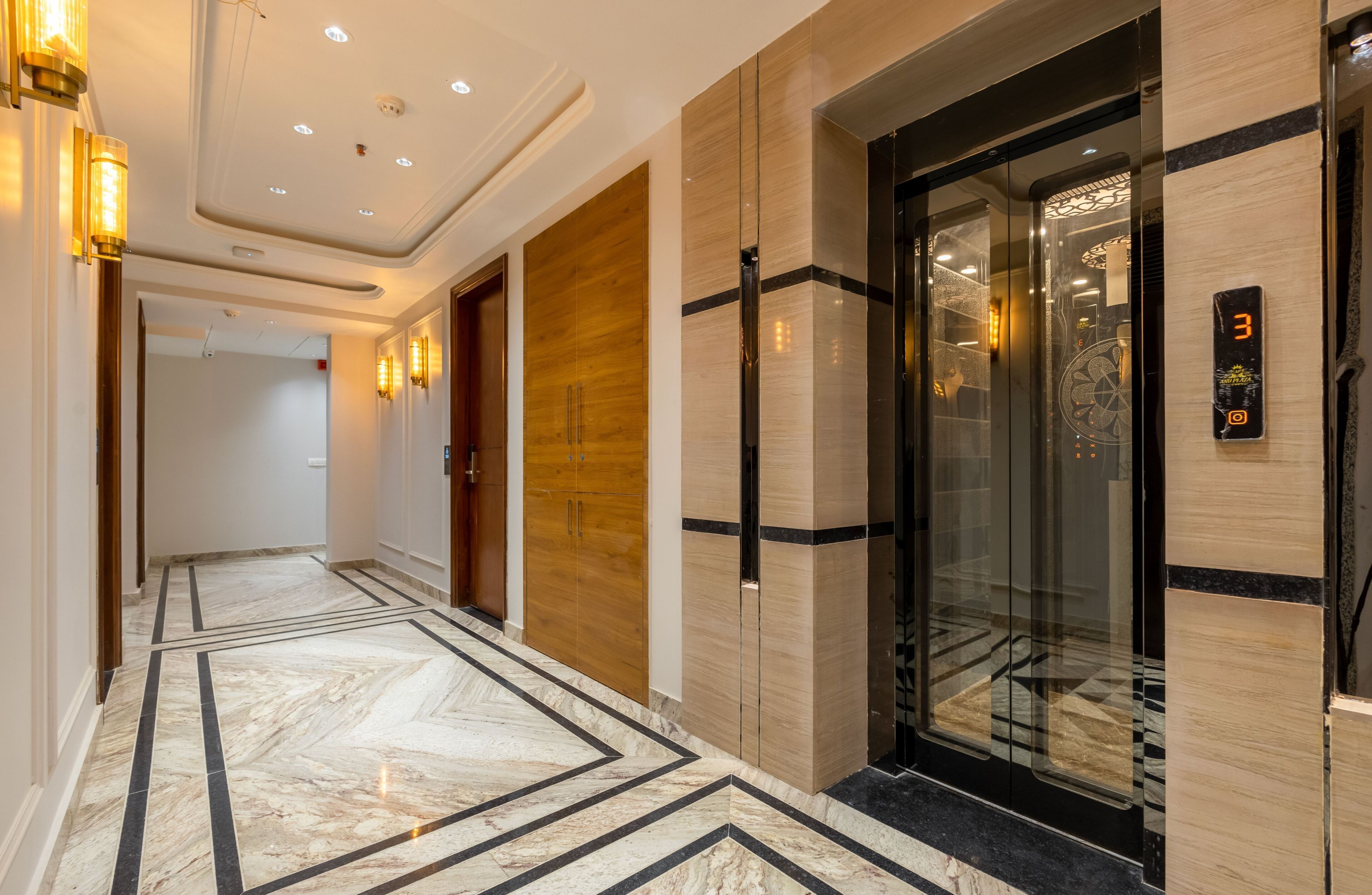 Een moderne lift met een digitaal display, een marmeren vloer met geometrische patronen en houten deuren.