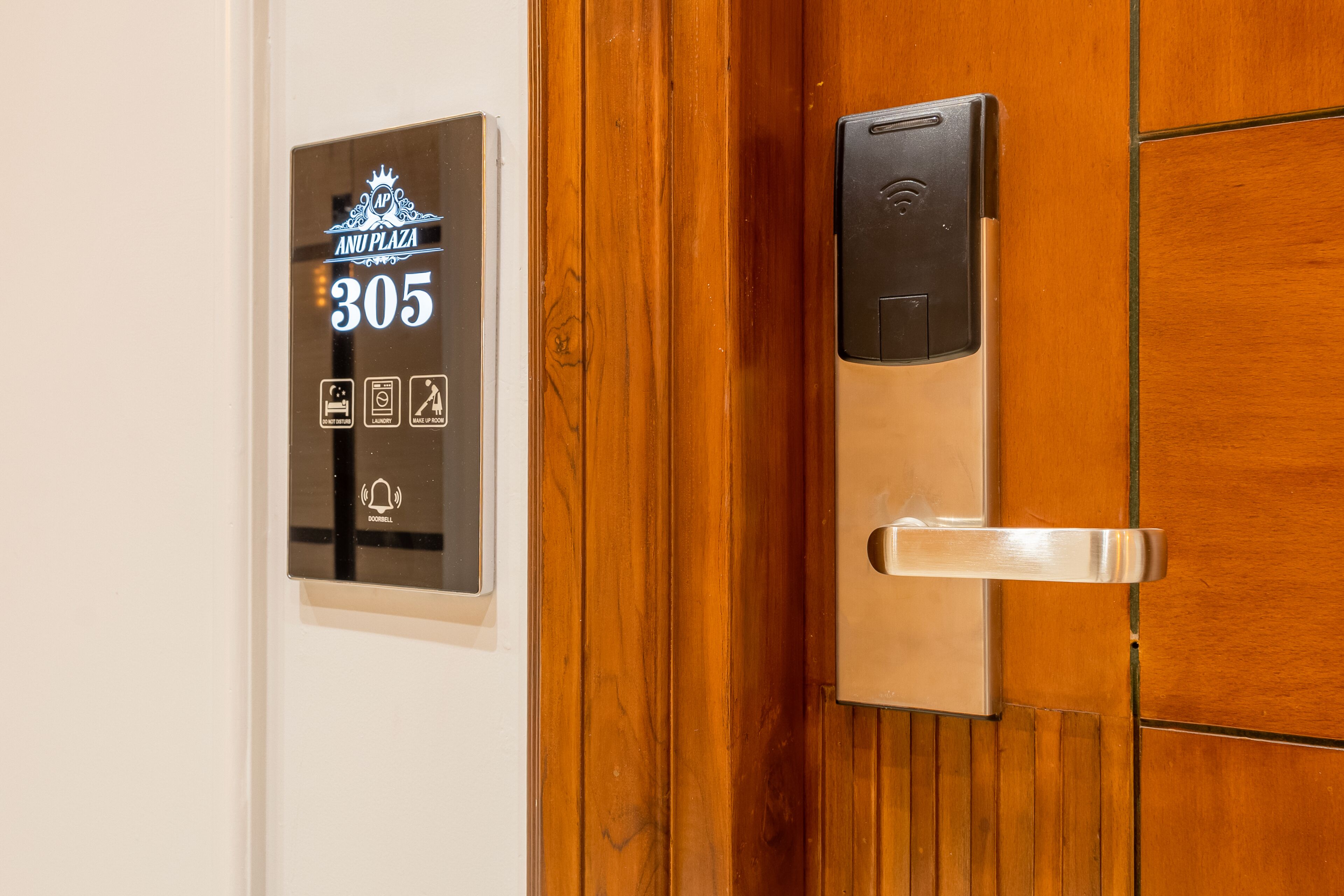Une porte de chambre d’hôtel dotée d’un écran numérique indiquant le numéro de chambre 305, d’un lecteur de carte magnétique et d’une poignée de porte.