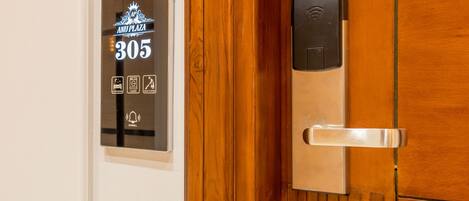 Une porte de chambre d’hôtel dotée d’un écran numérique indiquant le numéro de chambre 305, d’un lecteur de carte magnétique et d’une poignée de porte.