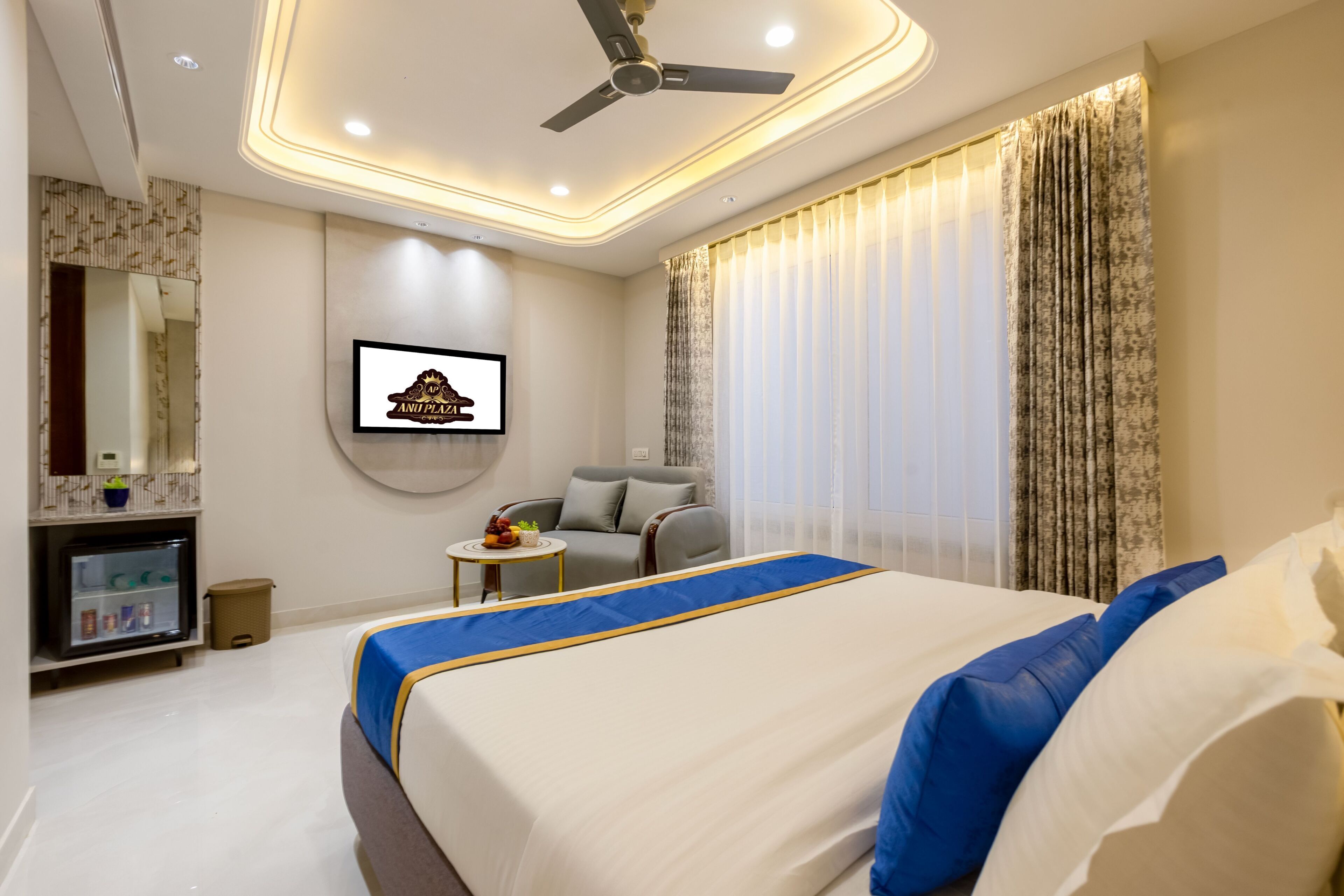 A hotel room with a bed, a desk, a chair, a television, and a ceiling fan.