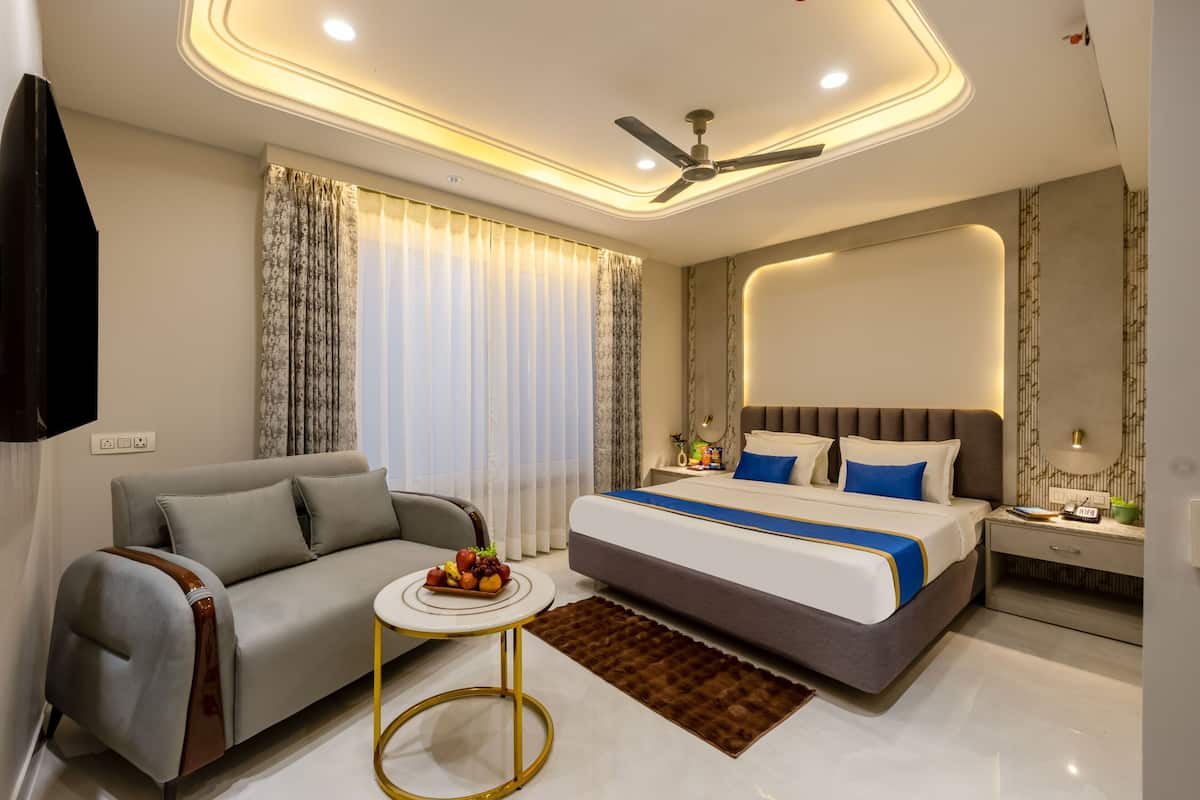 A modern hotel room with a bed, sofa, bedside table, and a ceiling fan.