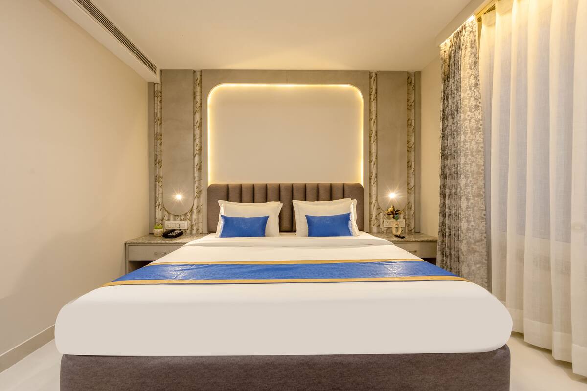 Habitación de hotel moderna con una cama grande, mesitas de noche y cabecero con iluminación integrada.